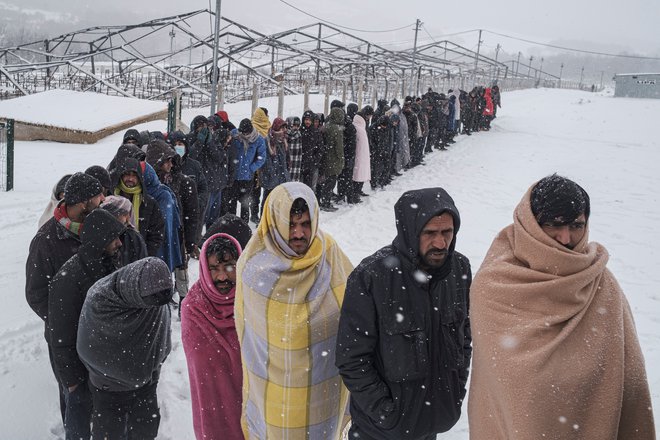 Migranti čakajo v vrsti za hrano med sneženjem v severozahodnem mestu Bihač v Bosni in Hercegovini, 11. januarja 2021. FOTO: REUTERS/Marko Djurica