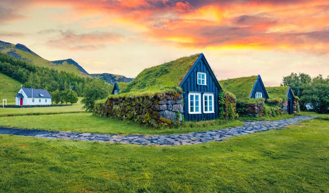 Tipičen pogled na travnate hiše na islandskem podeželju. Dramatičen poletni sončni vzhod v vasi Skogar na jugu Islandije v Evropi. Foto: Shutterstock