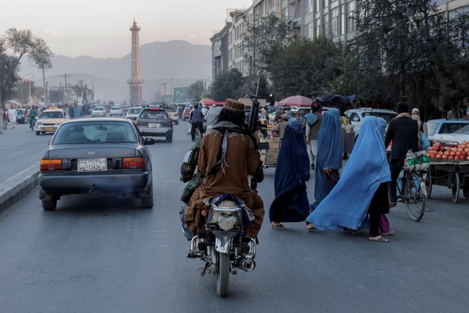 Skupina žensk v burkah in član talibanov na motorju. Foto: Jorge Silva / Reuters
