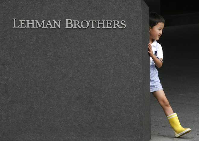 A boy plays behind a sign of Lehman Brothers Holdings at the company's branch in Tokyo September 16, 2008. The Tokyo Stock Exchange on Tuesday ordered the Japan unit of investment bank Lehman Brothers Holdings Inc to halt securities and derivatives tradin