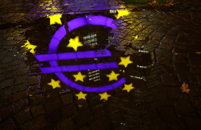 The euro sign in front of the former headquarters of the European Central Bank (ECB) is reflected in a puddle during heavy rain in Frankfurt, Germany, November 20, 2017.  REUTERS/Kai Pfaffenbach - RC1939D91FD0