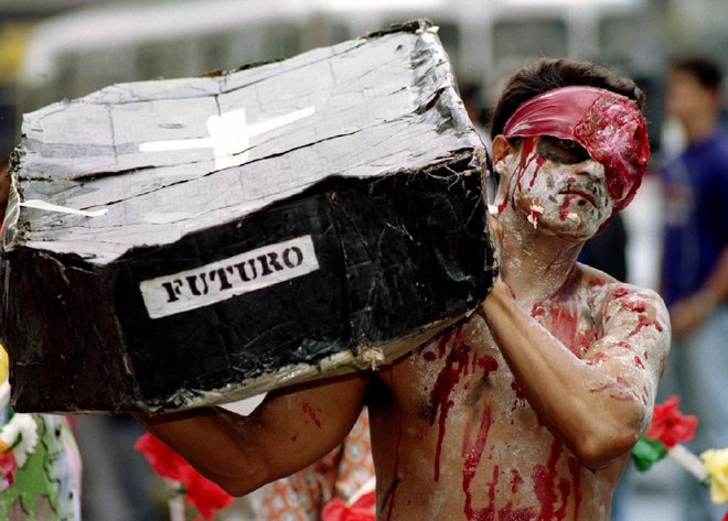 A Venezuelan man made up as a corpse carries a cardboard coffin as hundreds of demonstrators march in Caracas July 20 to protest against soaring levels of violent crime. About 40 people are murdered every weekend in the capital, mainly in poor shanty-town