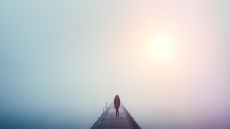 Fotografija: Woman crossing the bridge over lake on a foggy winter day.