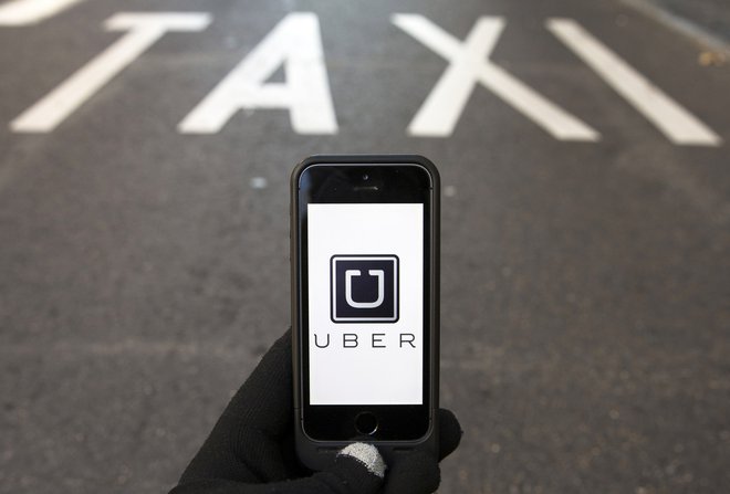 The logo of car-sharing service app Uber on a smartphone over a reserved lane for taxis in a street is seen in this file photo illustration taken in Madrid on December 10, 2014. The U.S. Department of Justice is pursuing a criminal  investigation of a May