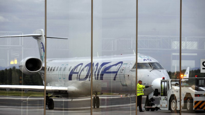 Fotografija: An Adria Airways Bombardier CRJ aircraft is reflected in the windows of the airport in Brnik May 29, 2013. Slovenian lawmakers approved government plans on June 21, 2013 to sell 15 state companies, including national airline Adria Airways, as part of the country's efforts to cut the budget deficit and avoid becoming the latest euro zone member to need an international bailout. Picture taken May 29, 2013. REUTERS/Srdjan Zivulovic (SLOVENIA - Tags: BUSINESS TRANSPORT POLITICS) - GM1E96M0EL501