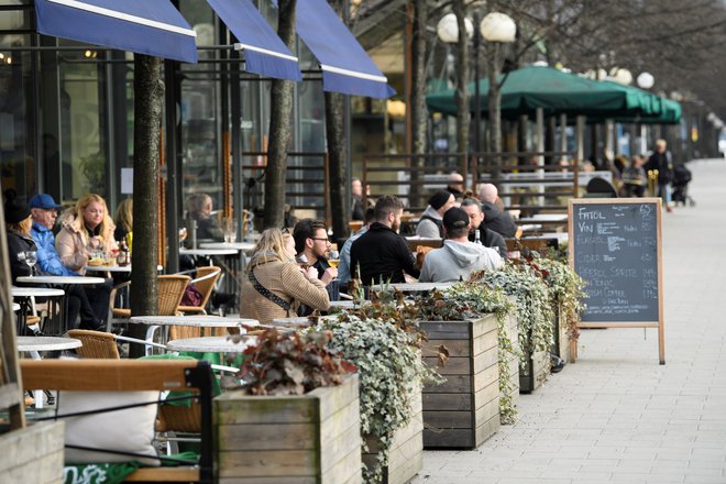 Ljudje sedijo v restavraciji na prostem v parku Kungstradgarden sredi novega vala covida-19 v Stockholmu na Švedskem. FOTO: REUTERS