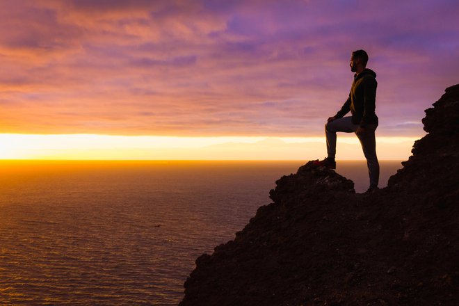 Silhouette of person witnessing unique twilight from mountain top. Successful, entrepreneur concepts