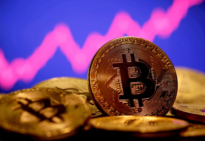 Bitcoin in graf v ozadju, ki nakazuje na njegovo rast, Foto: Reuters