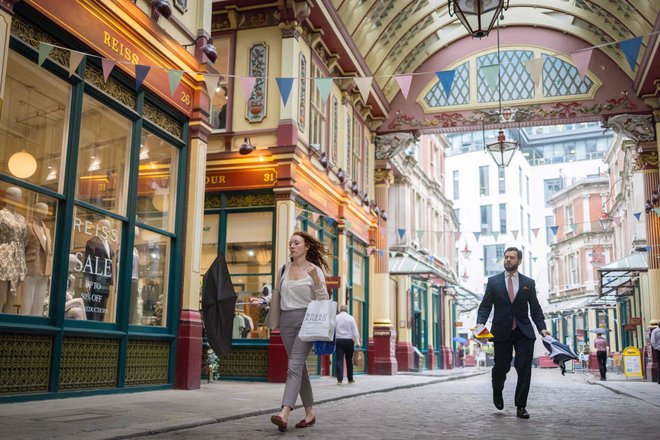 People walks past shops and restaurants at Leadenhall Market in the City of London. (Photo by Tolga Akmen / AFP)