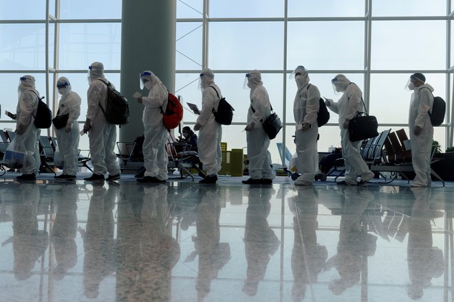 Potniki morajo nositi zaščitne obleke na letališču v Hongkongu, 9. julij, 2021. Foto: Thomas Peter/Reuters<br />
 