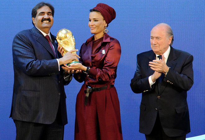 Šejk Hamad bin Khalifa Al-Thani, emir Katarja in njegova žena, šejkinja Moza bint Nasser Al-Missned prejemata pokal svetovnega nogometnega prvenstva od nekdanjega predsednika Fife, Josepha Blatterja, ob razglasitvi, da bo Katar leta 2022 gostil nogometni spektakel, 2. december 2010. Foto: Fabrice Coffrini / AFP
