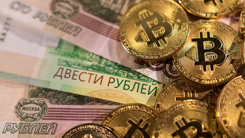 Fotografija: Bankovci ruskega rublja in bitcoin. Foto: Dado Ruvic / Reuters
