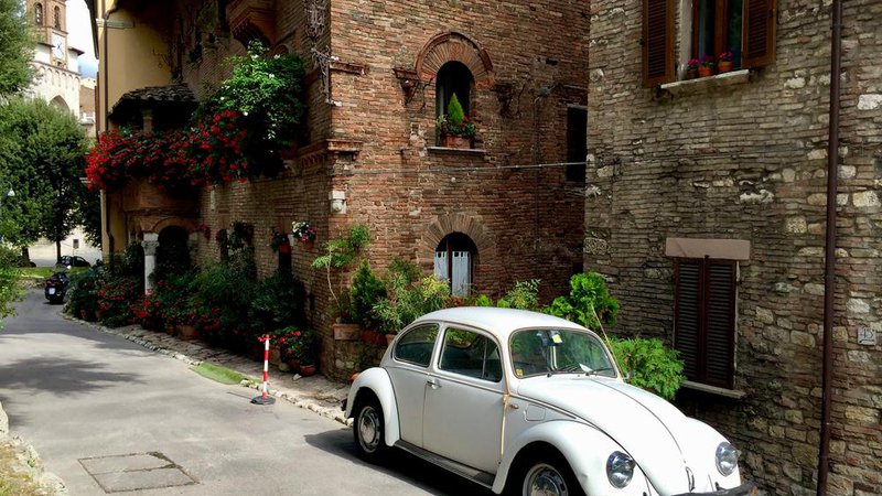 Fotografija: Street in Perugia, Umbria. Retro car, medieval building, geranium in pot, stone wall. Foto: Shutterstock
