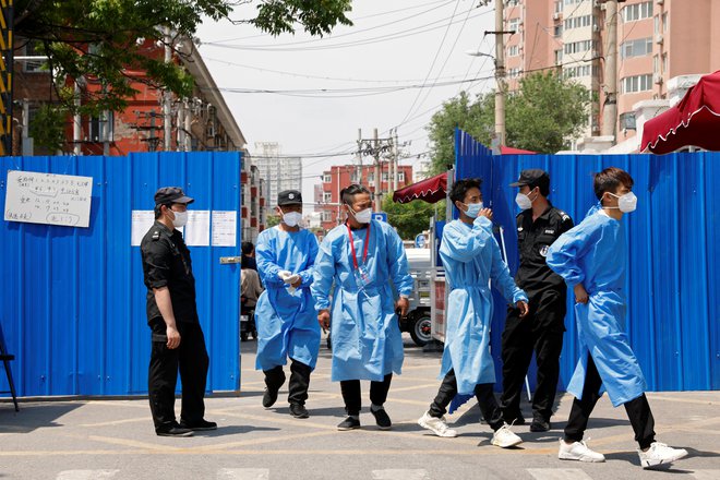 Workers in protective suits walk through the gate of a barricaded residential area under lockdown, amid the coronavirus disease (COVID-19) outbreak in Beijing, China May 17, 2022. Foto: CARLOS GARCIA RAWLINS/Reuters
