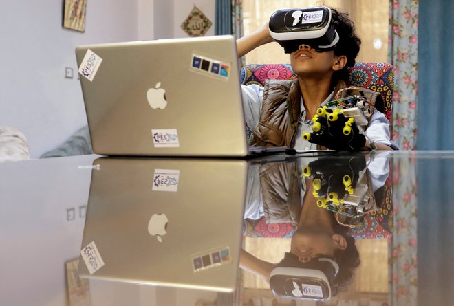 Omar Wael, 13-letni egiptovski razvijalec, uporablja napravo za navidezno resničnost (VR), medtem ko dela na svojem prenosnem računalniku, 23. maj 2022. Foto: Mohamed Abd El Ghany / Reuters
